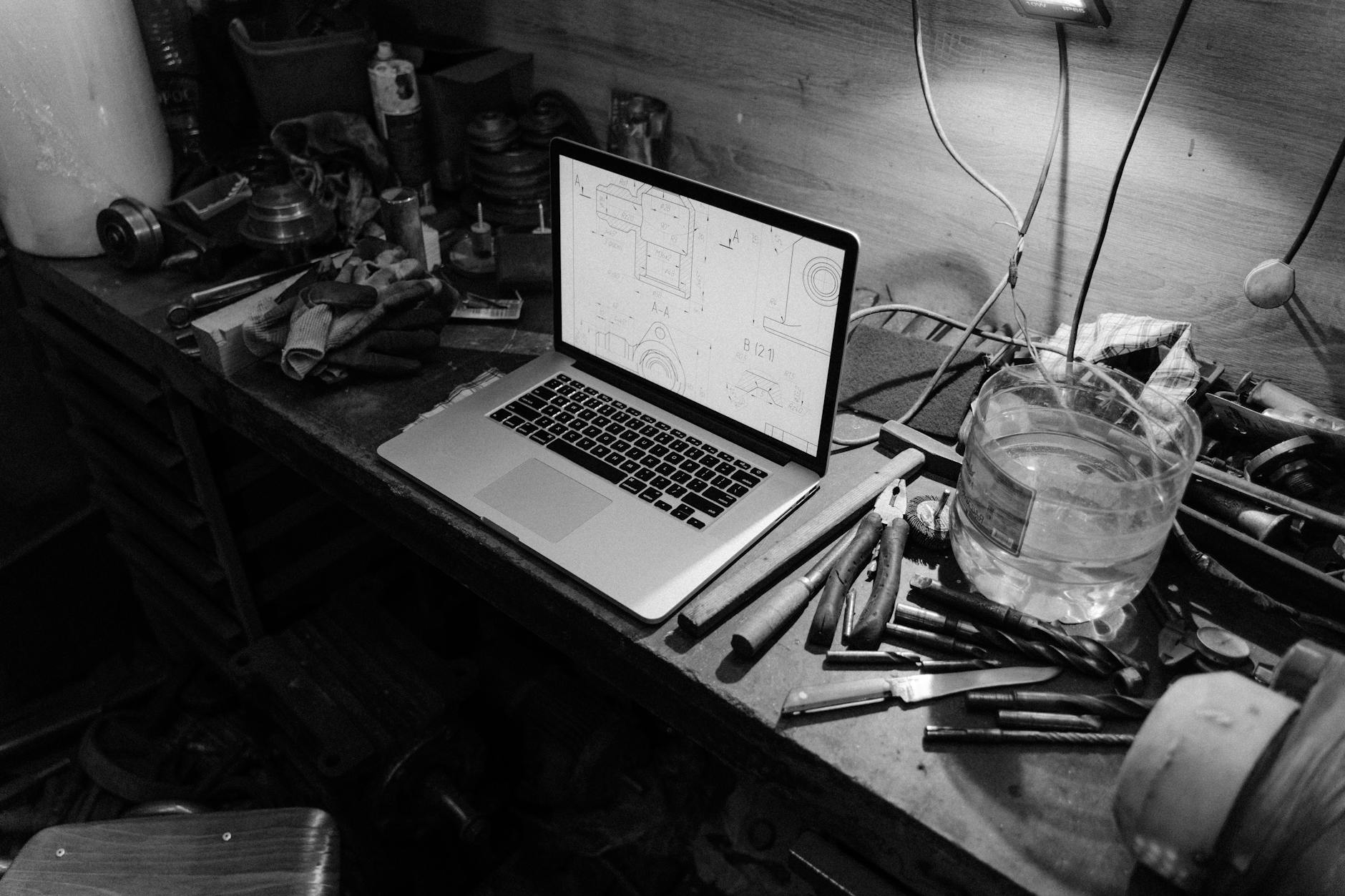 a grayscale photo of a laptop on a work table